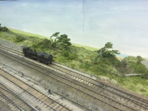 A model locomotive passing scenic trees